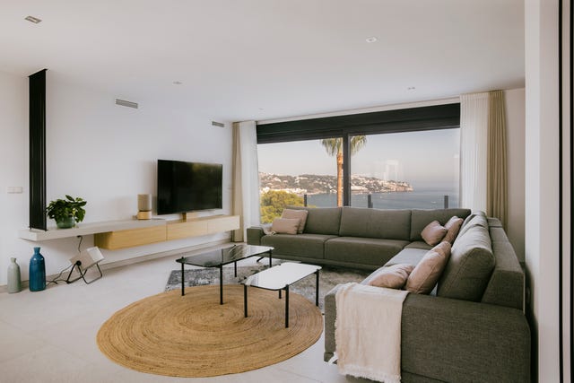 salón con sofá rinconero gris, mesas nido y alfombra redonda de fibras