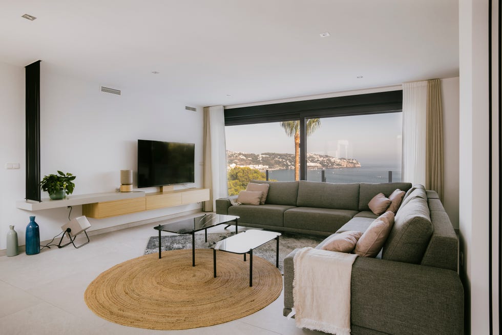 salón con sofá rinconero gris, mesas nido y alfombra redonda de fibras
