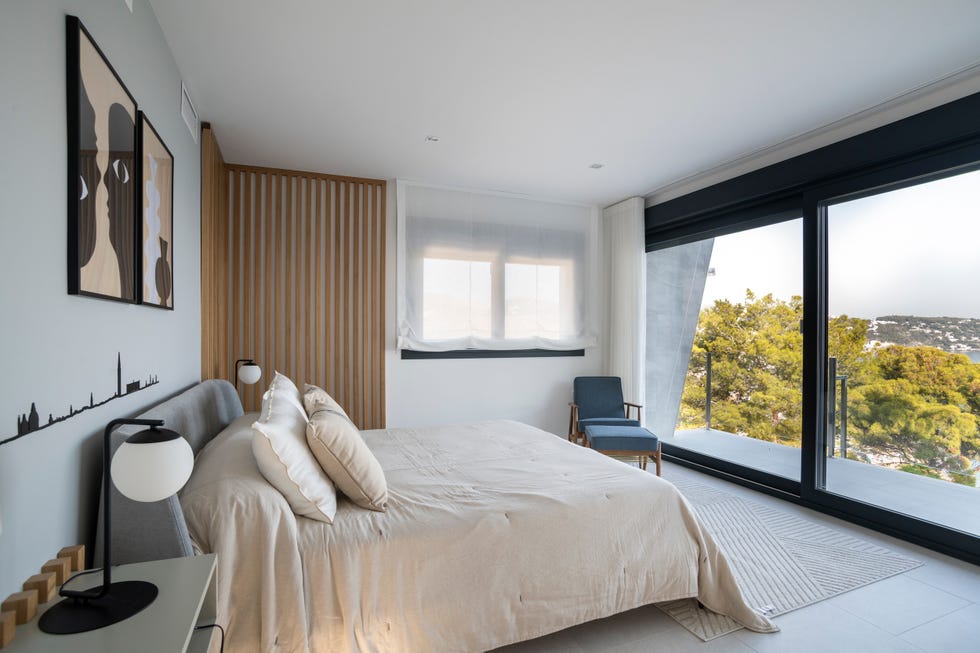 dormitorio moderno con cabecero gris y ventanales correderos