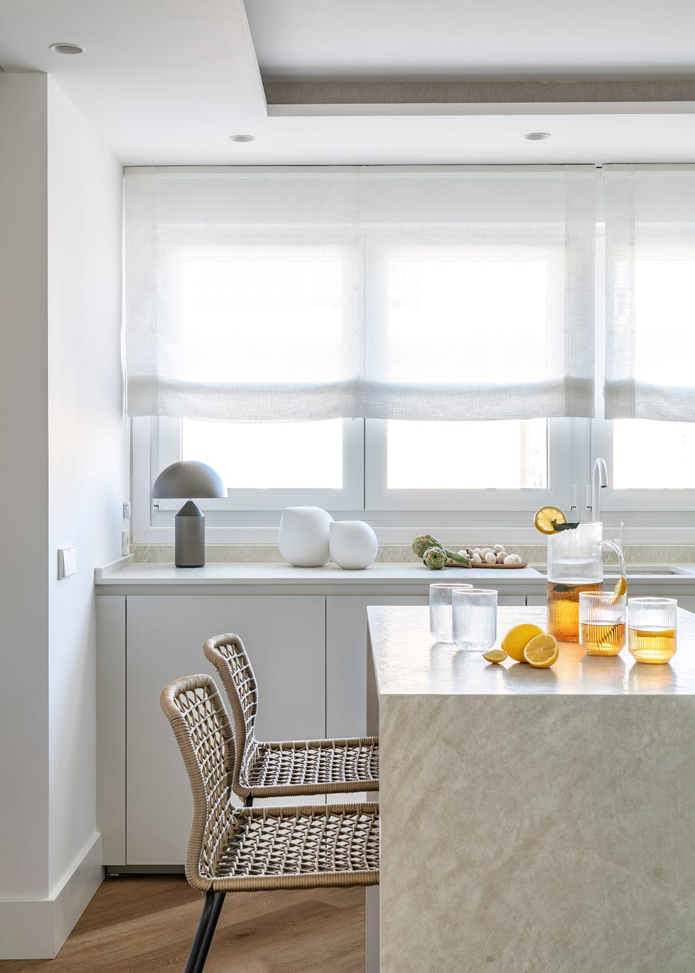 cocina con armarios blancos e isla central con taburetes