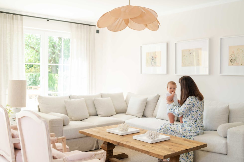 salón con sofá rinconera gris, mesa de centro de madera, butacas clásicas y lámpara de techo con pétalos