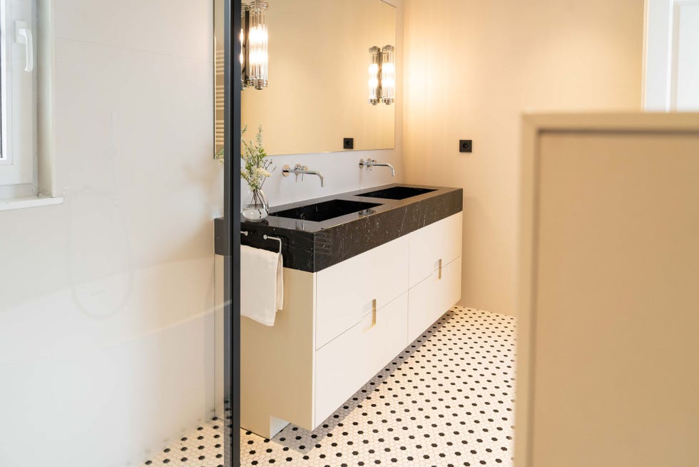 baño con lavabo doble de mármol negro y suelo de azulejos panal de abeja