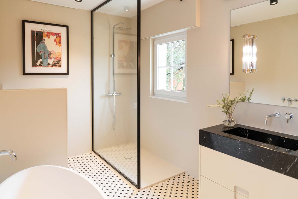 baño con lavabo de mármol negro, ducha y bañera