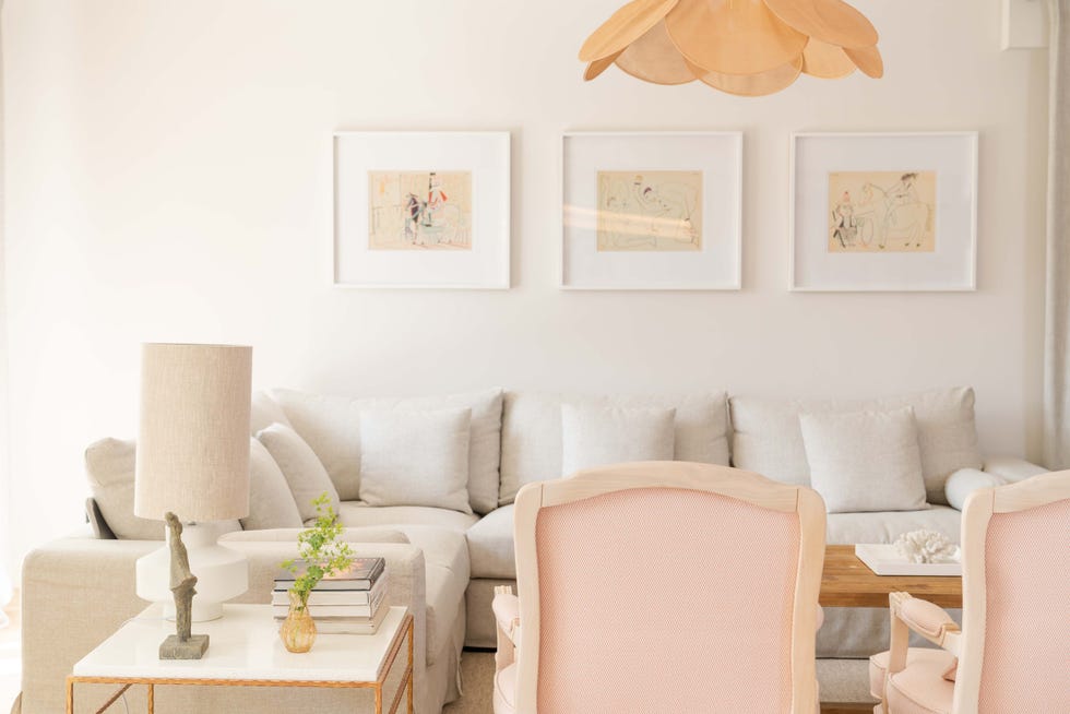 salón con sofá rinconera gris, mesa de centro de madera, butacas clásicas y lámpara de techo con pétalos