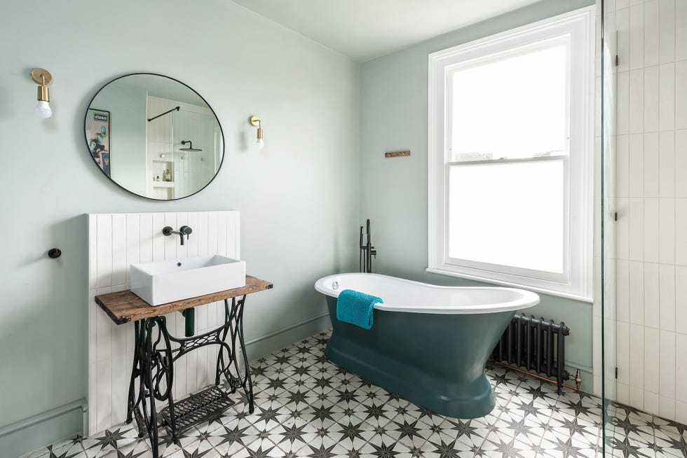 baño vintage con máquina de coser antigua, bañera exenta clásica y suelo de baldosas hidráulicas