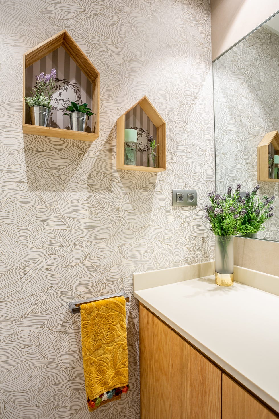 baño decorado con papel pintado con dibujo abstracto y estanterías con forma de casitas