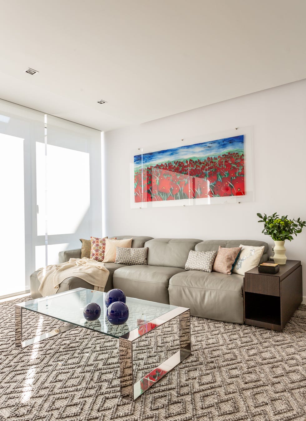 salón de diseño moderno con sofá con chaise longue de piel gris y mesa de centro de cristal
