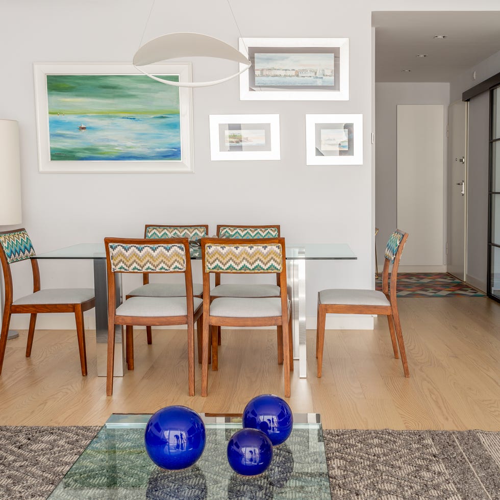 comedor moderno con mesa de cristal y sillas de madera y tapizado en zig zag