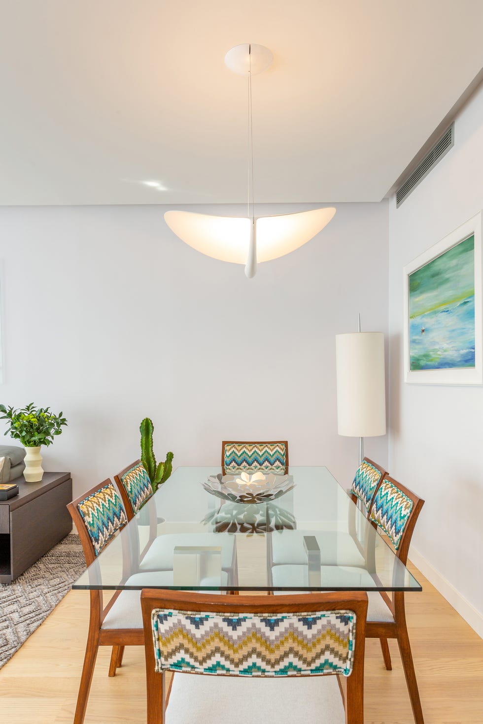 comedor moderno con mesa de cristal y sillas de madera y tapizado en zig zag
