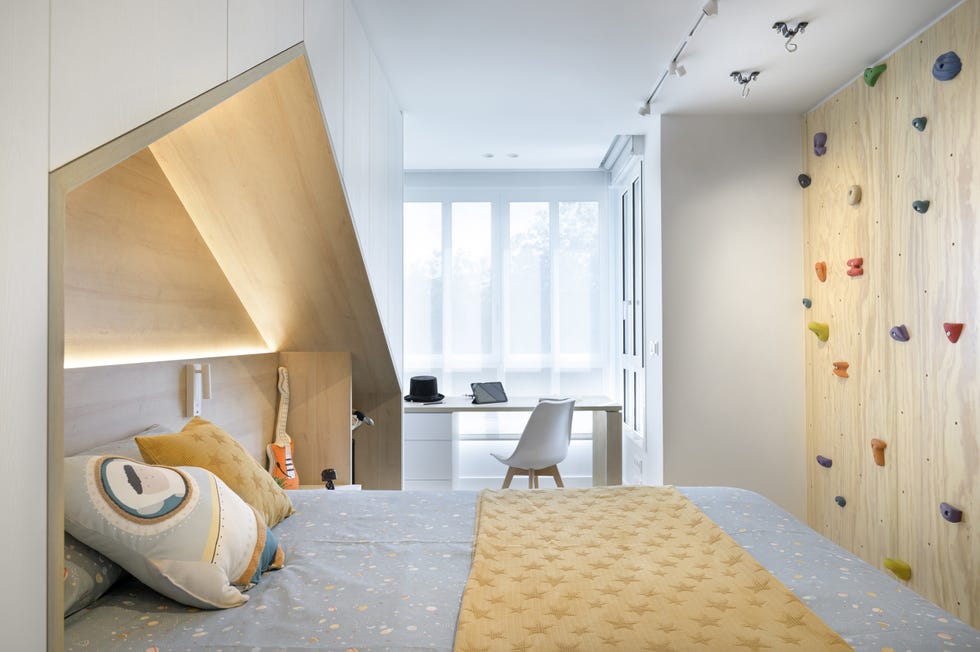 habitación infantil con escritorio y rocódromo en la pared