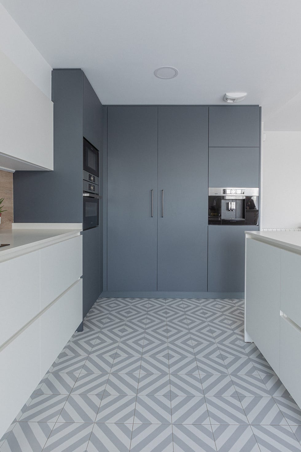 cocina moderna con armarios blancos y grises y suelo con baldosas geométricas