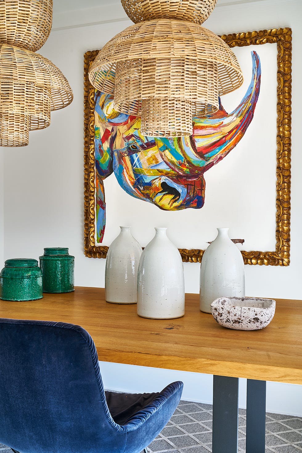 comedor con mesa de madera con patas de hierro, sillas de terciopelo azul y lámparas de techo de fibras