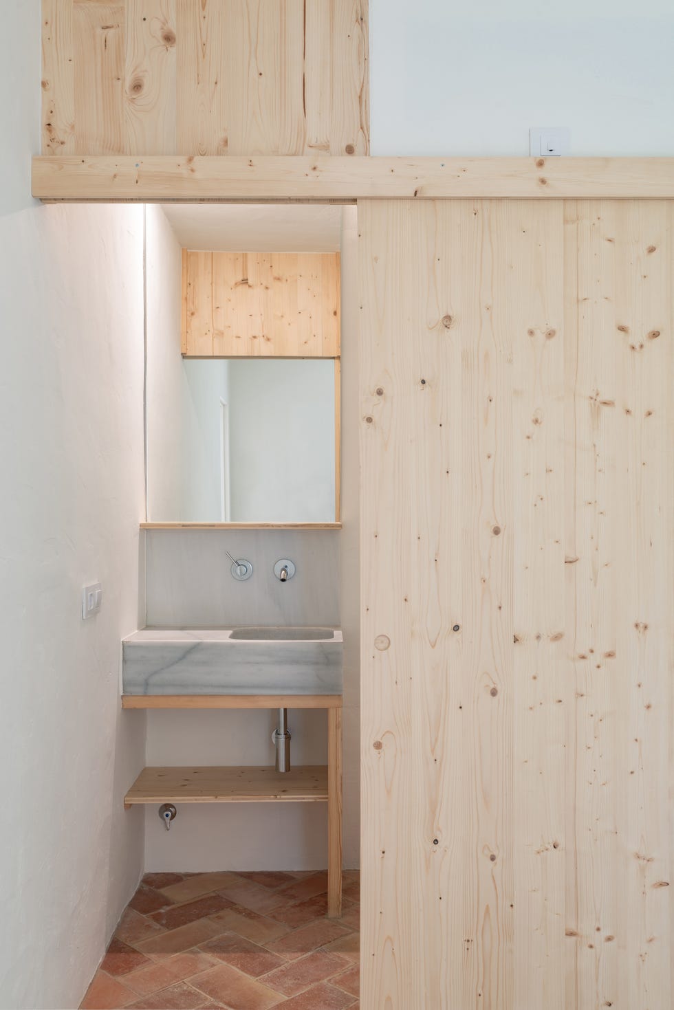 baño con puerta corredera de madera de pino y lavabo de mármol