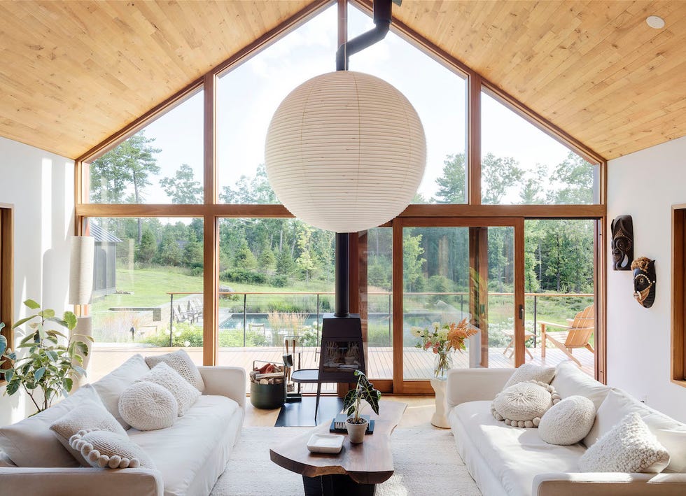 salón con tejado de madera a dos aguas, ventanales de suelo a techo y sofás blancos