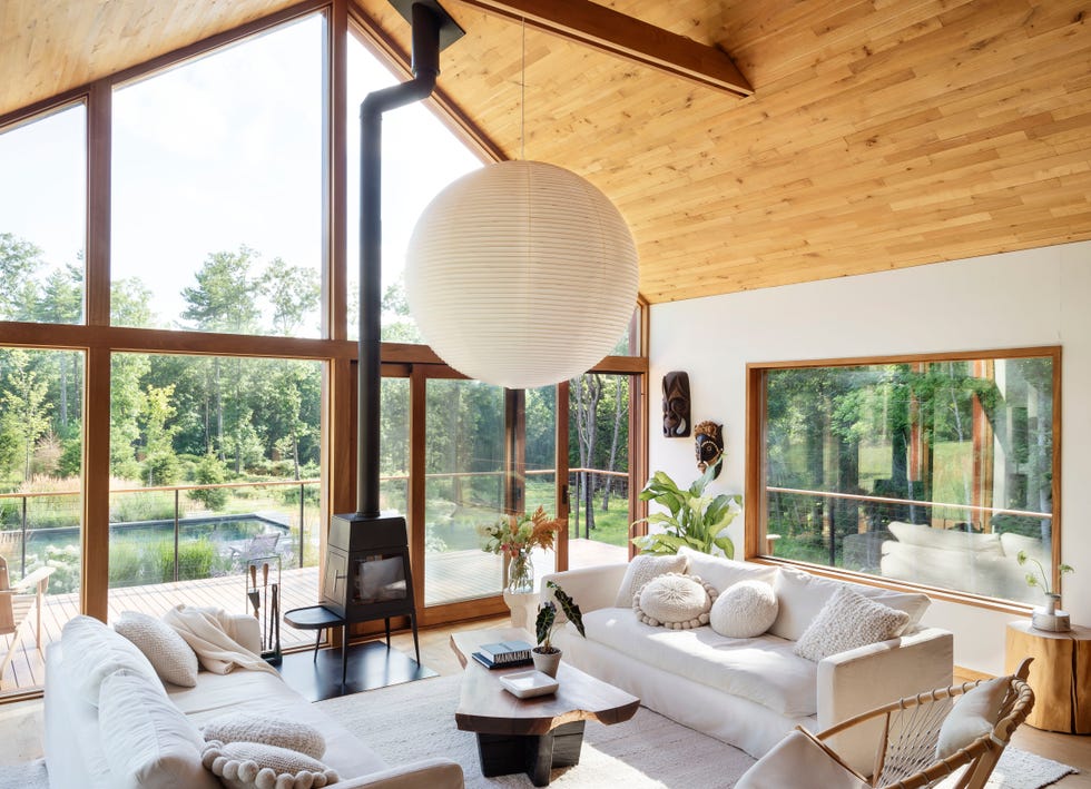 salón con tejado de madera a dos aguas, ventanales de suelo a techo y sofás blancos
