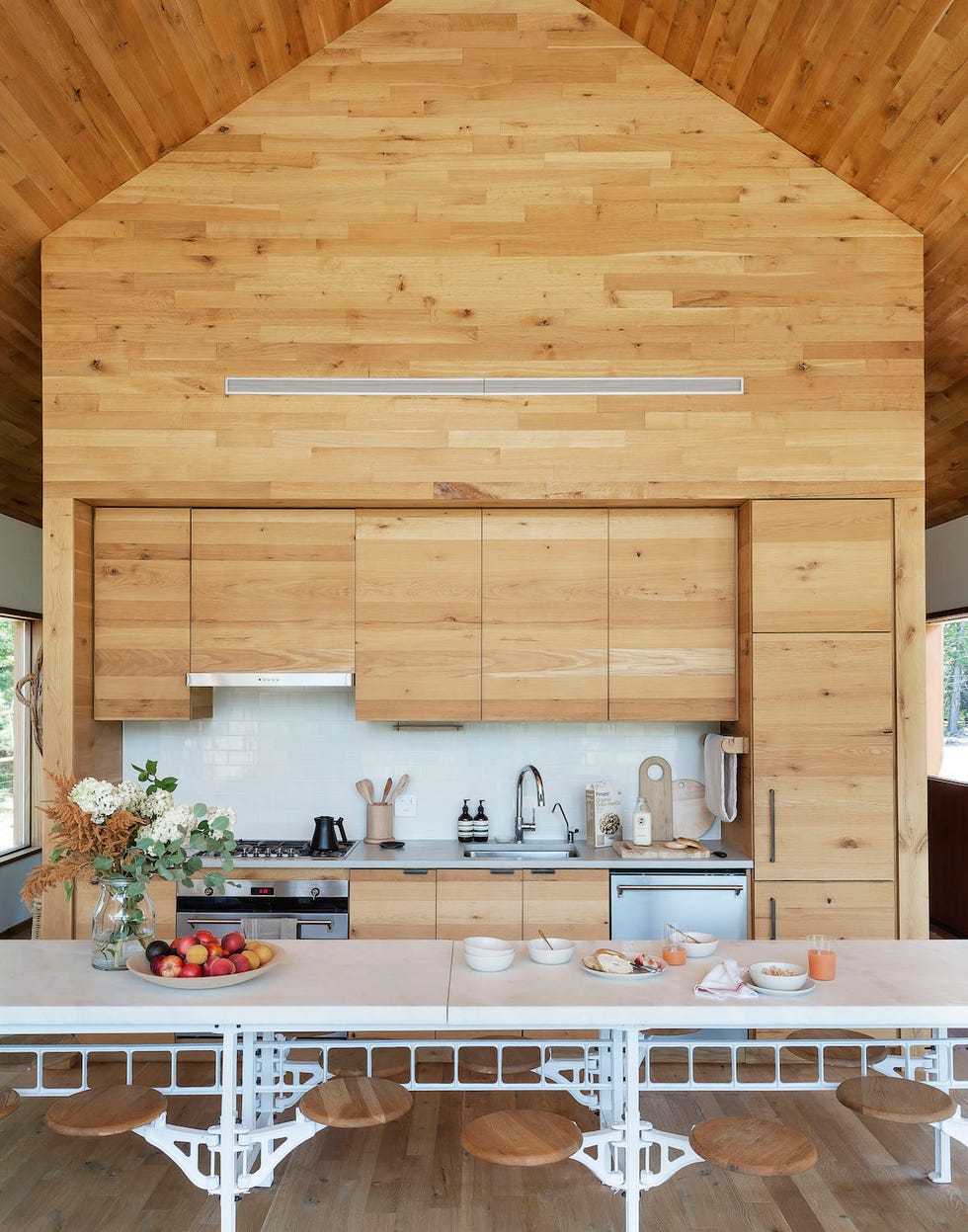 cocina abierta con armarios de madera y frente de azulejos blancos tipo metro