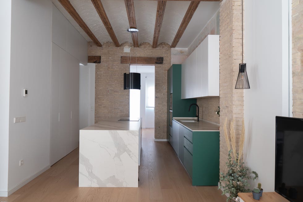 cocina verde con isla central de mármol y vigas vistas