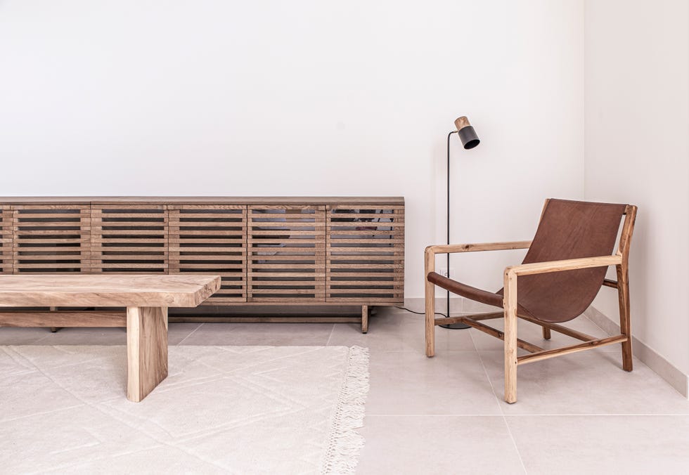 mesa de centro y aparador de madera y butaca de piel junto a lámpara de pie