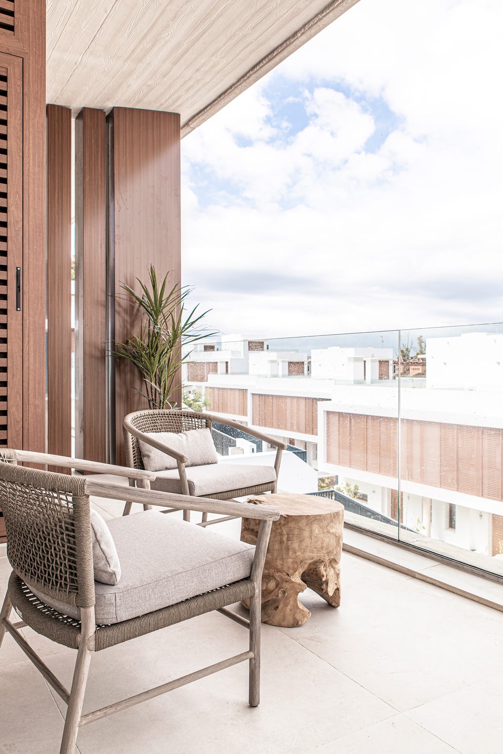 terraza con dos butacas de fibras y mesa auxiliar de madera tipo tronco