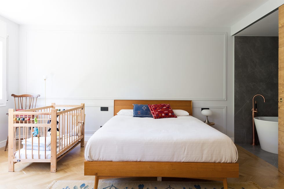 dormitorio con baño en suite y cuna de madera
