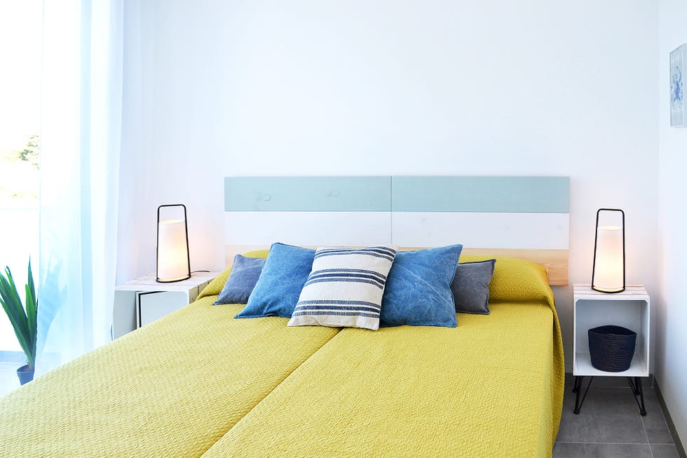 Dormitorio de estilo playero con funda nórdica mostaza y cabecero de madera a tres colores