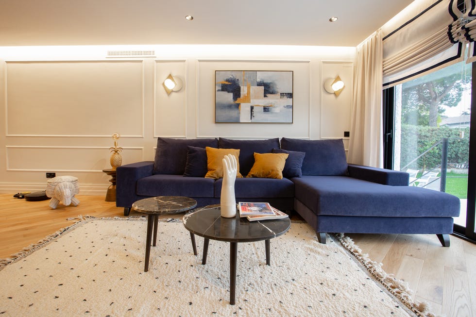 salón decorado con sofá de terciopelo azul con chaise longue y mesas nido