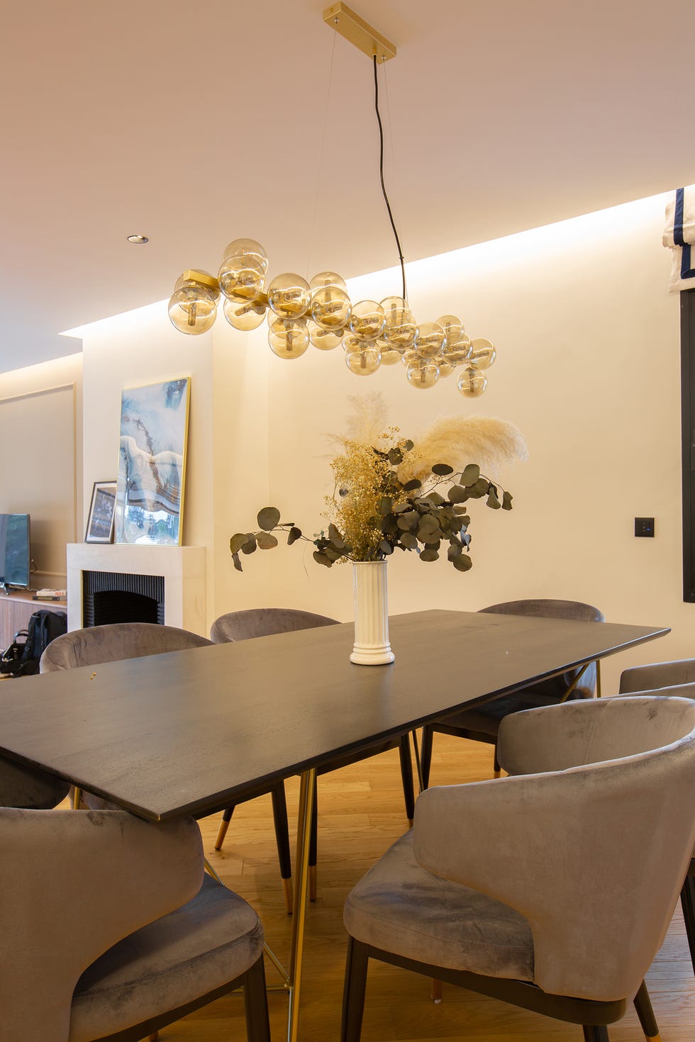 mesa de comedor de madera con patas doradas, sillas de terciopelo y lámpara colgante con bolas