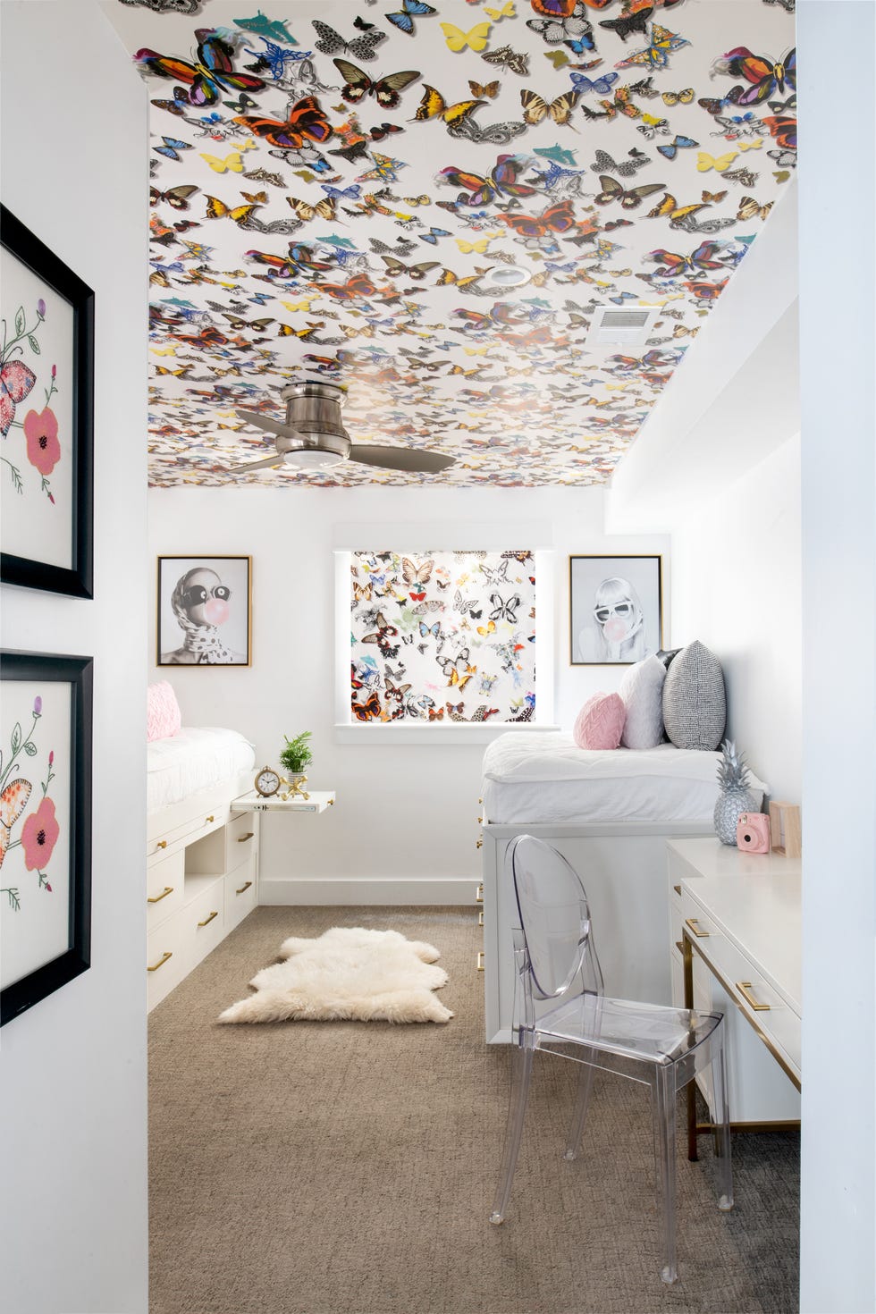habitación infantil con dos camas nido y techo con papel pintado con mariposas