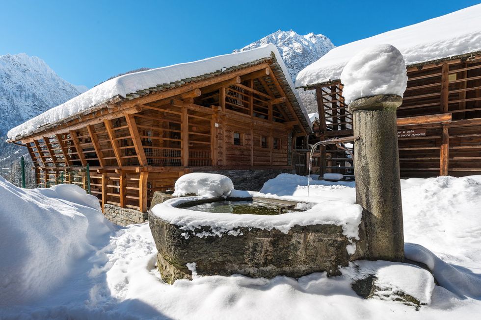 a building with a large snow covered roof and a large rock in front of it
