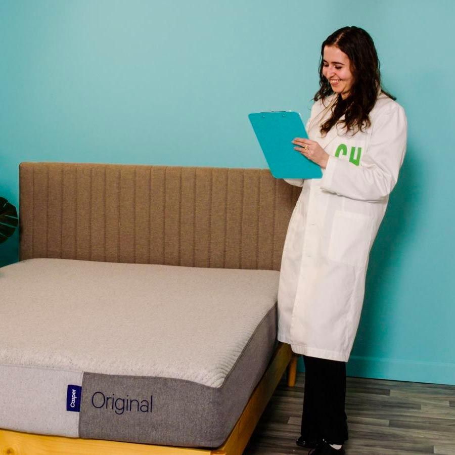 a person in a white lab coat reviewing a casper mattress