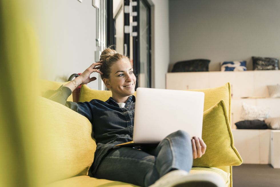casual businesswoman using laptop on couch in office lounge