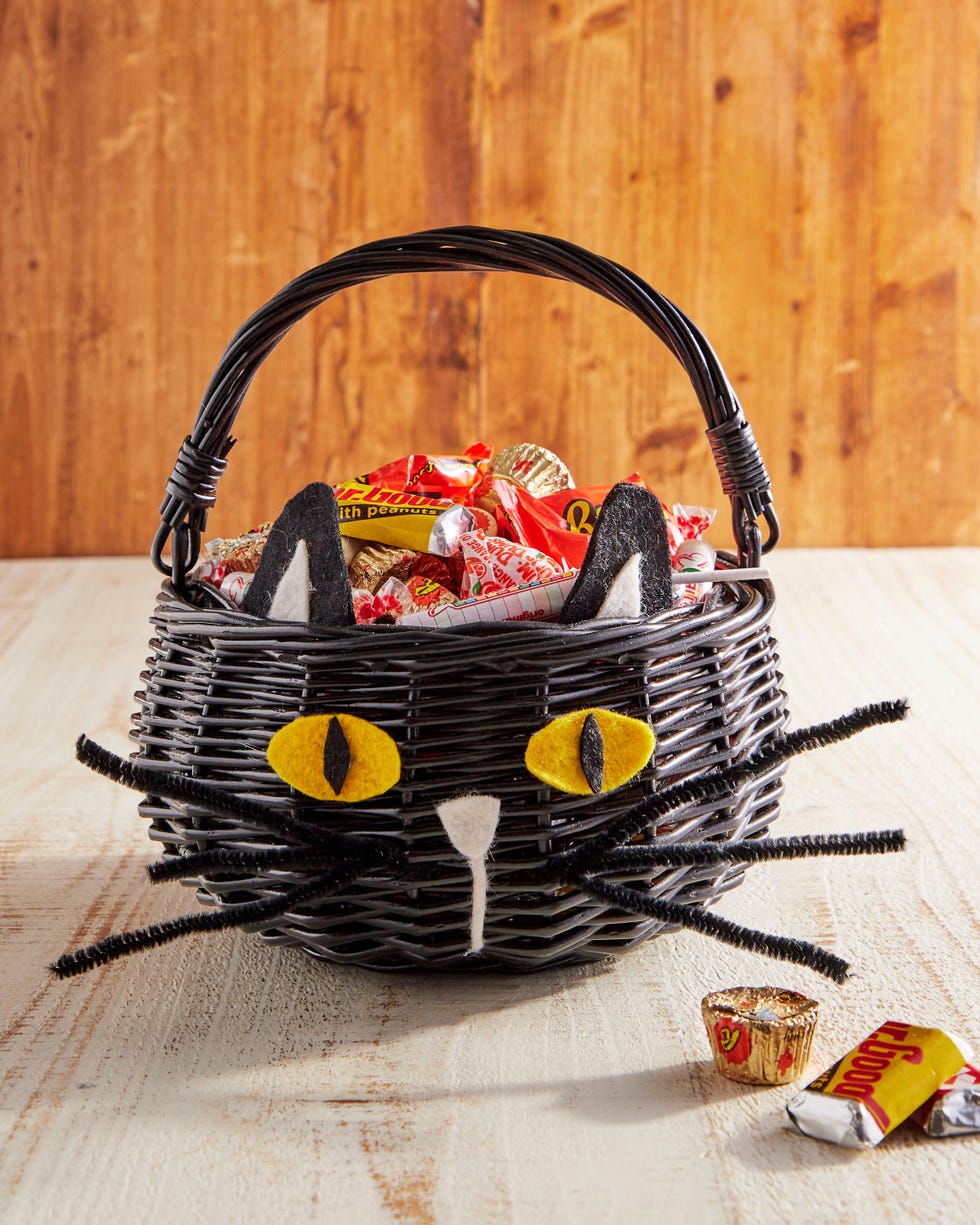 a black basket with a handles and felt pieces added so that it looks like a black cat