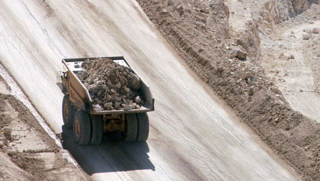 Caterpillar dump truck climbs the haul road on a gold mine with a new load of ore for processing