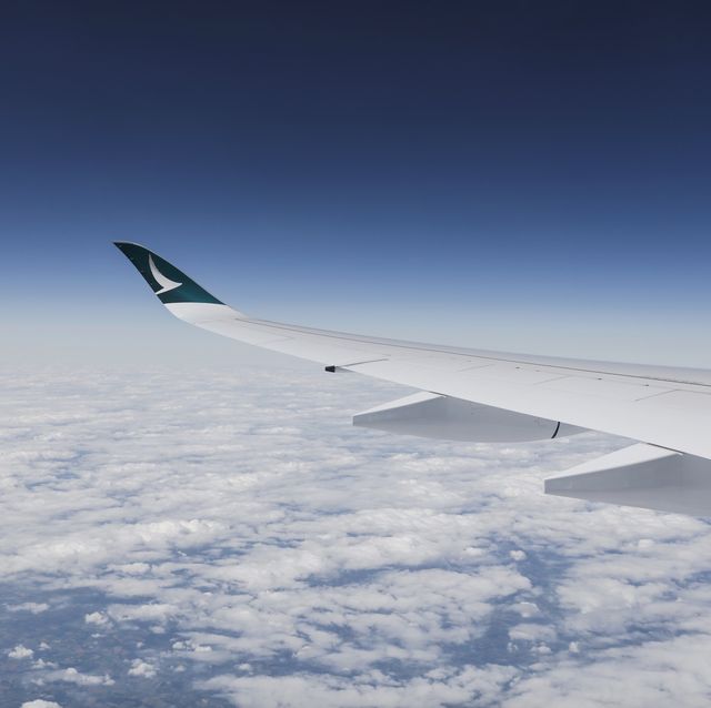 avión de cathay pacific volando por encima de nubes