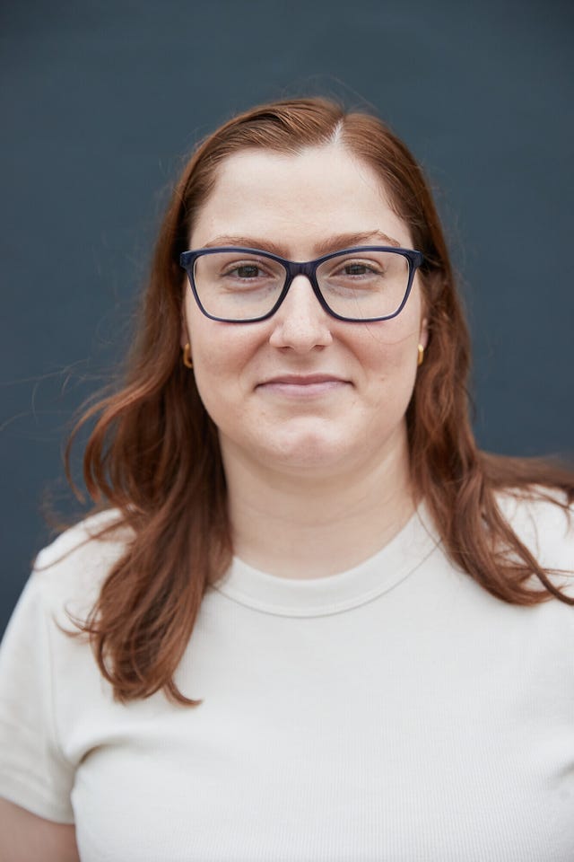 a woman wearing glasses and a white tshirt smiles