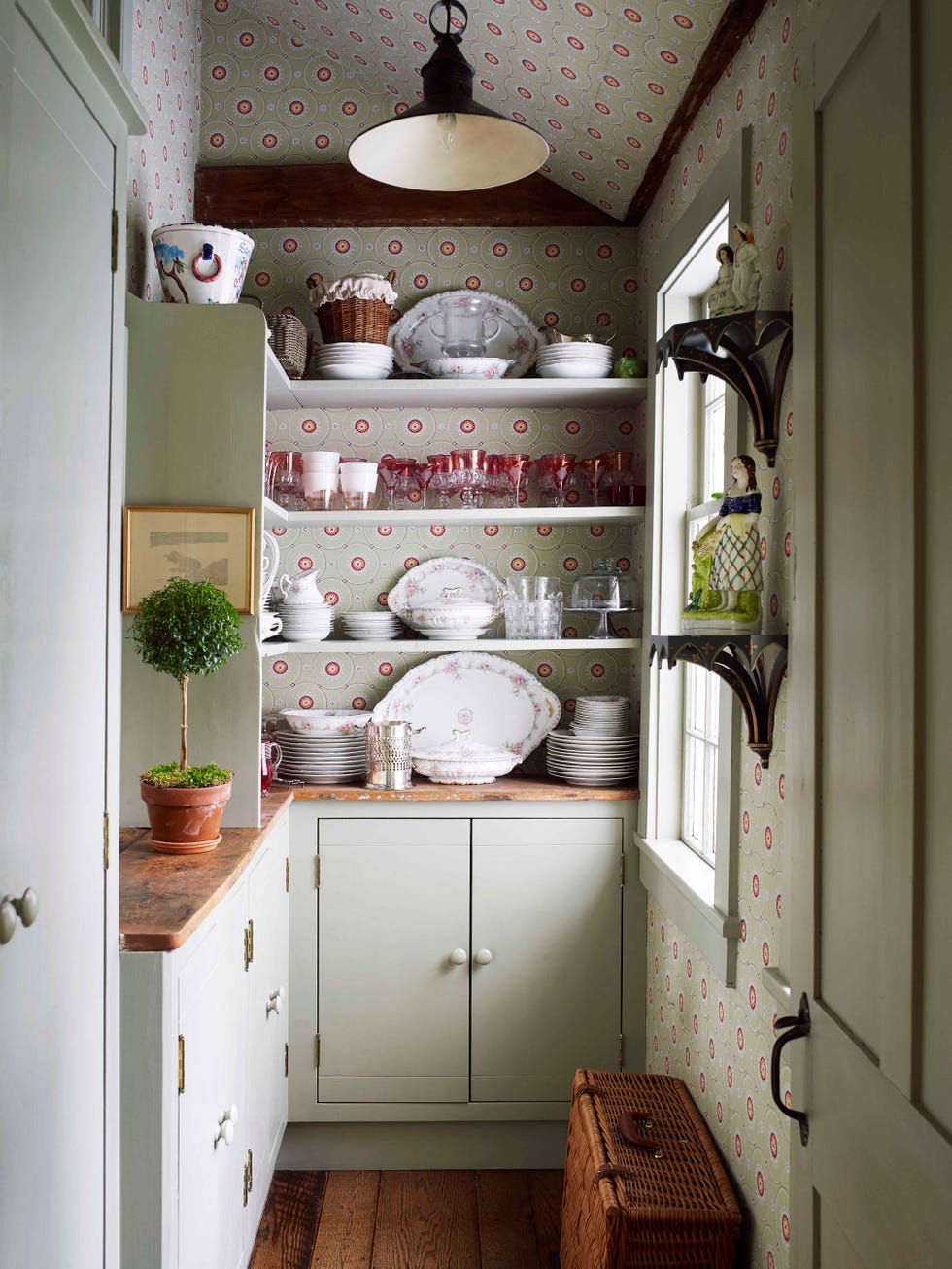a butler’s pantry walls are covered in a recolored historic parisian pattern open shelves are filled with glasses and dishware