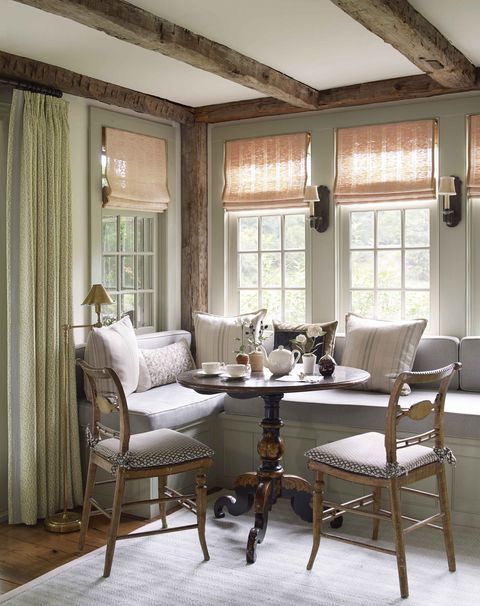 a window banquette with a small round table and two chairs is set for breakfast