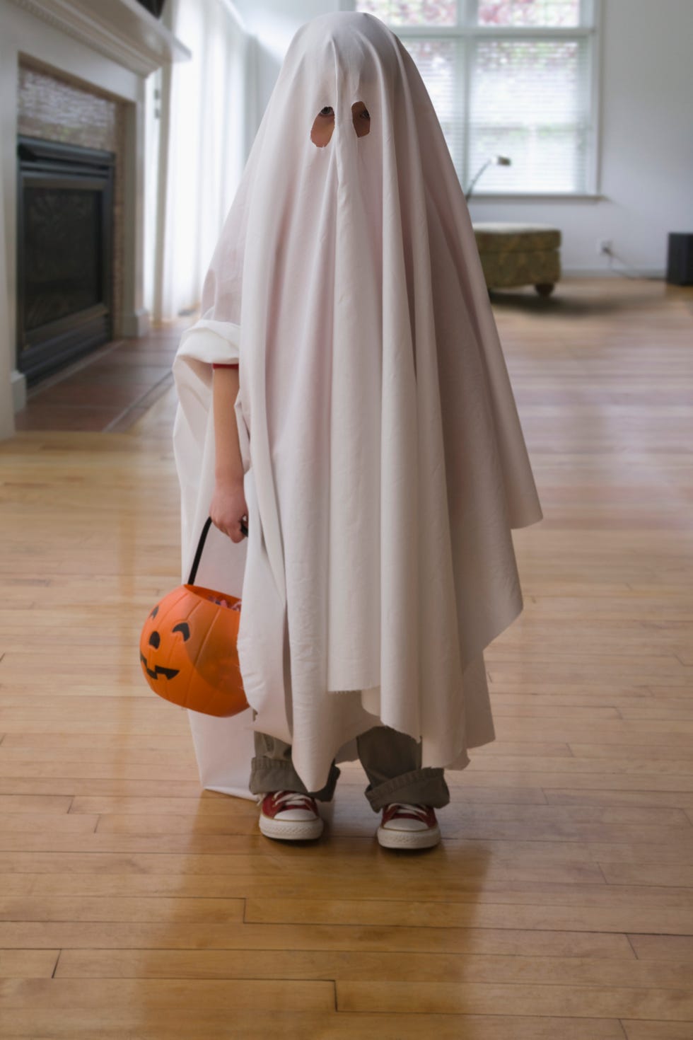 Caucasian boy dressed in ghost costume holding jack o'lantern