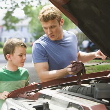 caucasian boy watching father work on car engine