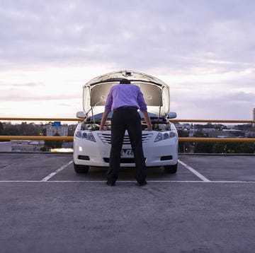 caucasian businessman checking underneath automobile hood