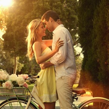 Caucasian couple hugging on bicycle