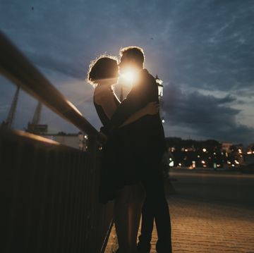 caucasian couple kissing near railing at night
