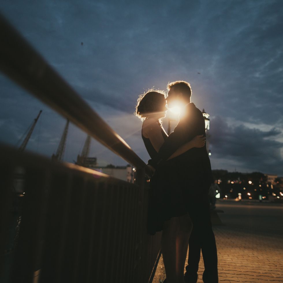 Caucasian couple kissing near railing at night