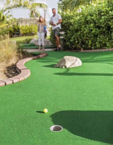 caucasian couple playing miniature golf
