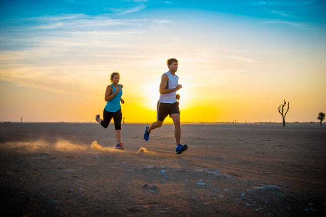 Caucasian couple running in desert