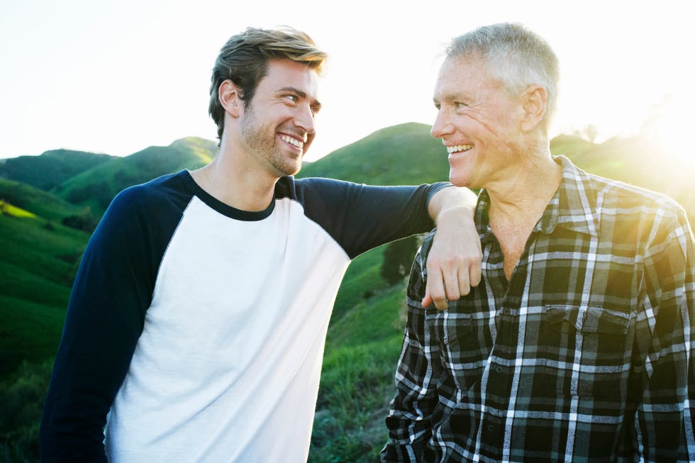 caucasian father and son smiling on rural hilltop