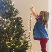caucasian girl hanging lights on christmas tree