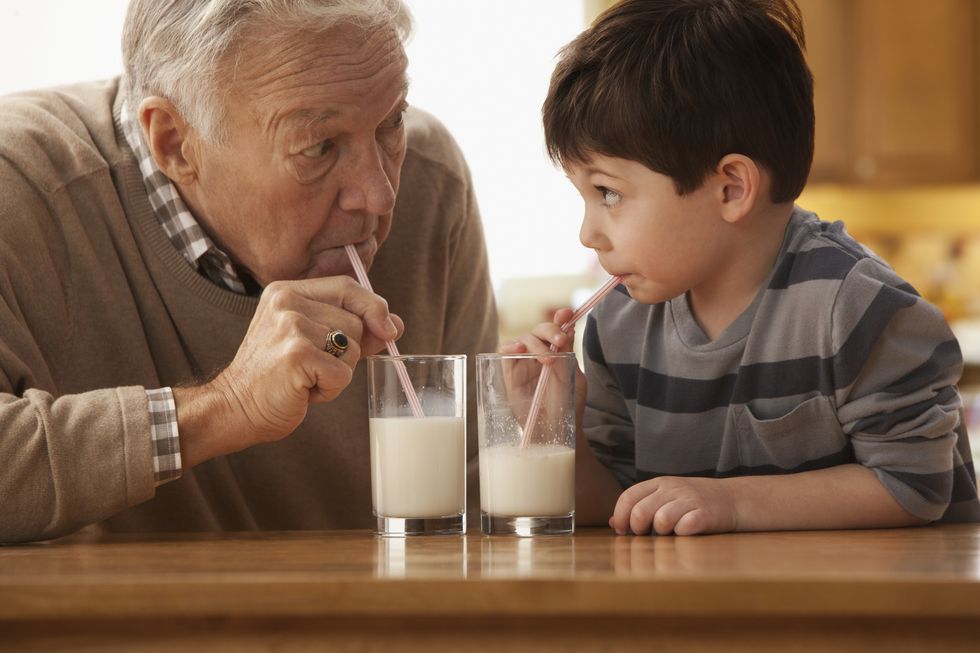 caucasian grandfather and grandson drinking milk together