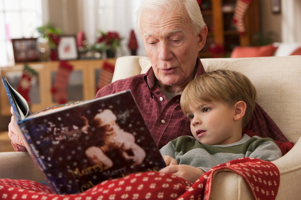 caucasian grandfather reading book to grandson