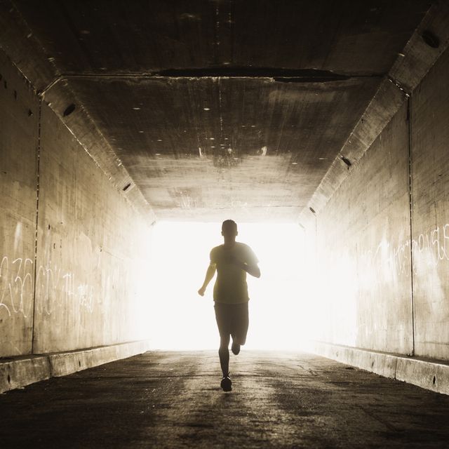 Caucasian man running in urban tunnel
